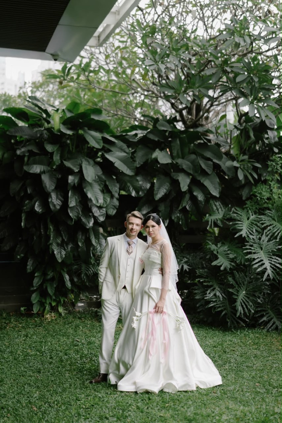 Luci et Adrien en tenue de mariage dans un jardin luxuriant